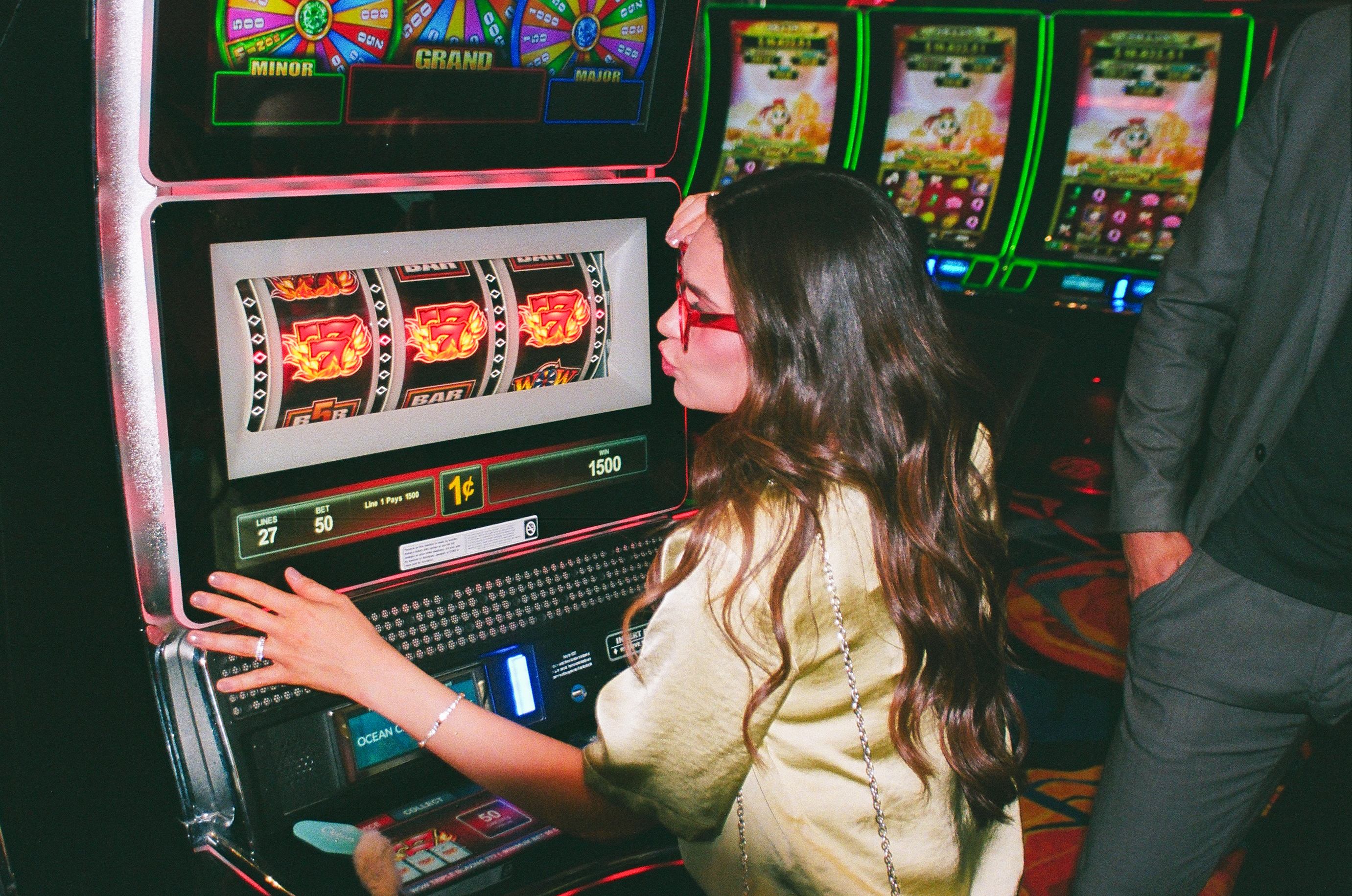 A woman wearing red glasses plays a slot machine at Ocean Casino Resort, watching the reels spin with anticipation.