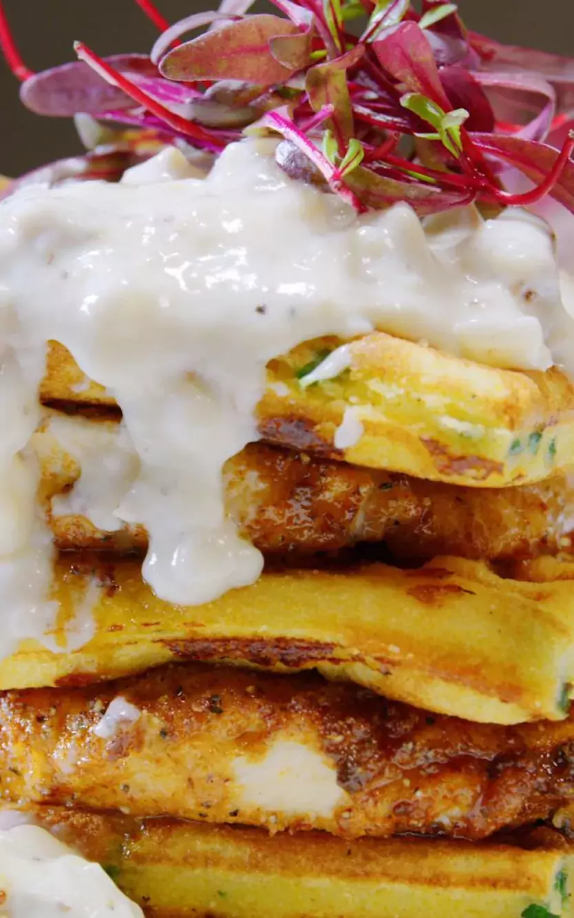 A stack of fluffy waffles and fried chicken on a plate at Harper's Chicken and Waffles