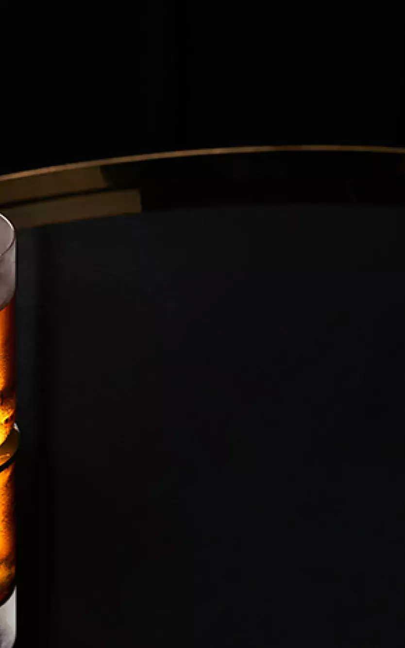 Cocktail sitting on a reflective surface with a dark background and Nola's Bar & Lounge logo on the right